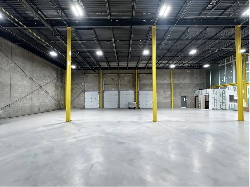 Warehouse interior: clear-span floor, yellow steel columns and four overhead doors