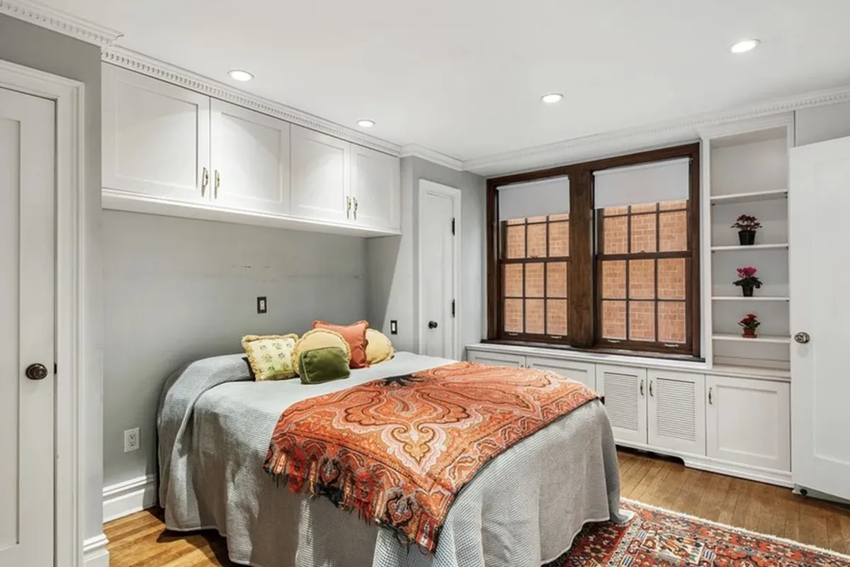 A bedroom in Apartment 3F at 170 East 78th Street with built-in cabinetry and a pair of casement windows