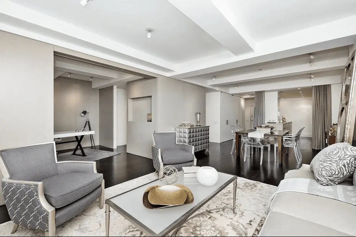 Living and dining area of a renovated pre-war condo at 40 East 61st Street, with dark hardwood floors and beamed ceilings