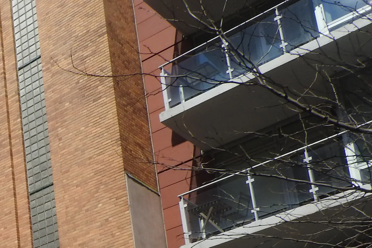 Glass balconies and terracotta-colored panels on the 13th Street facade of 425 East 13th Street, beside the brick school next door