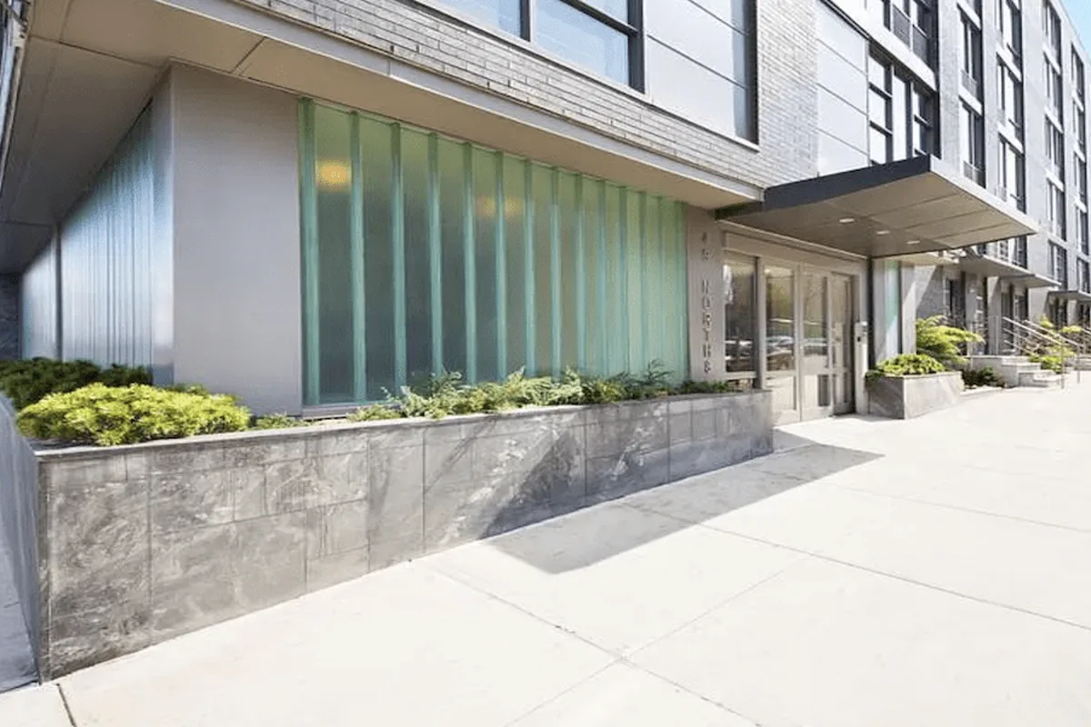 Exterior street view of 49 North 8th Street condominium building entrance with glass and metal facade, Williamsburg, Brooklyn