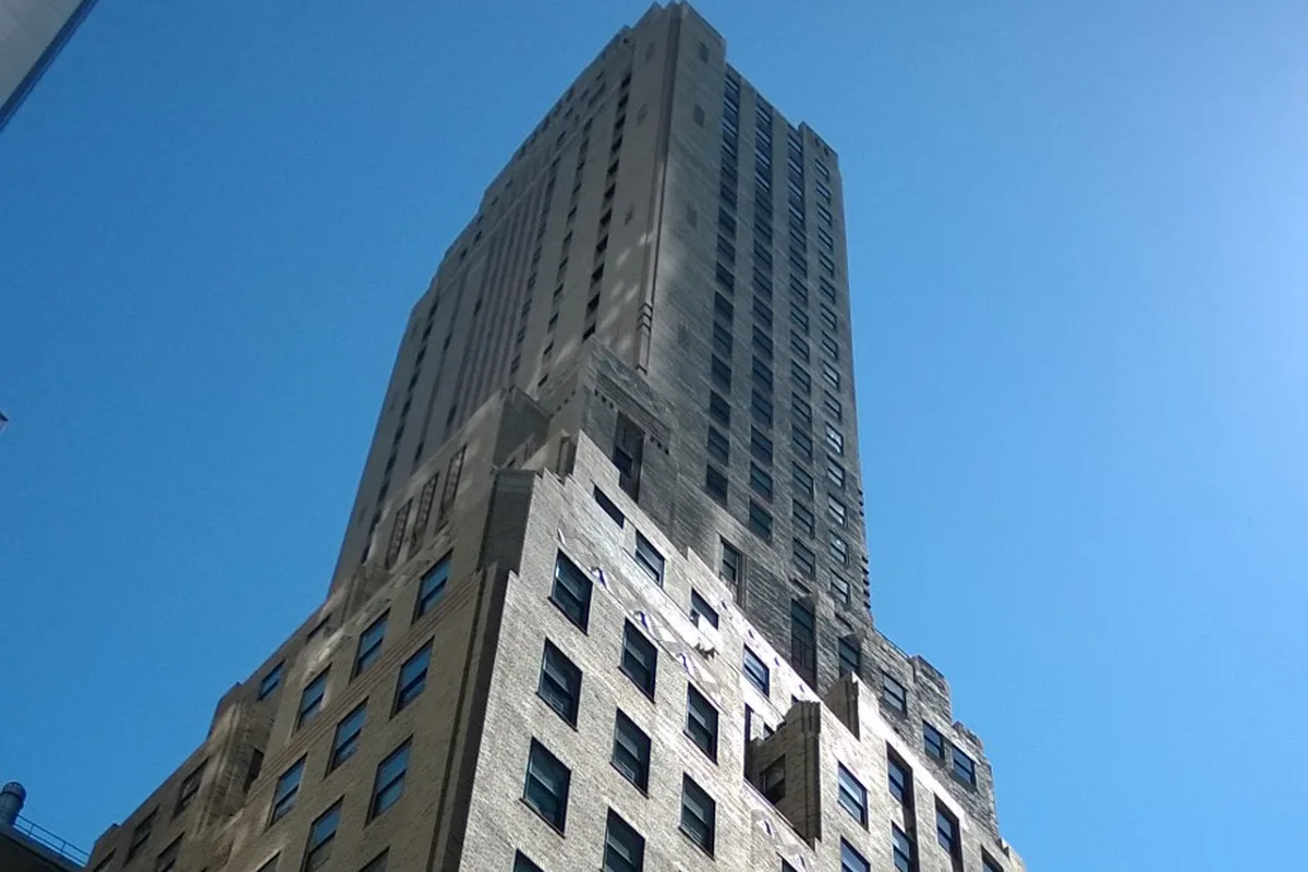Looking up at the setbacks of 88 Greenwich Street's beige brick tower against a blue sky