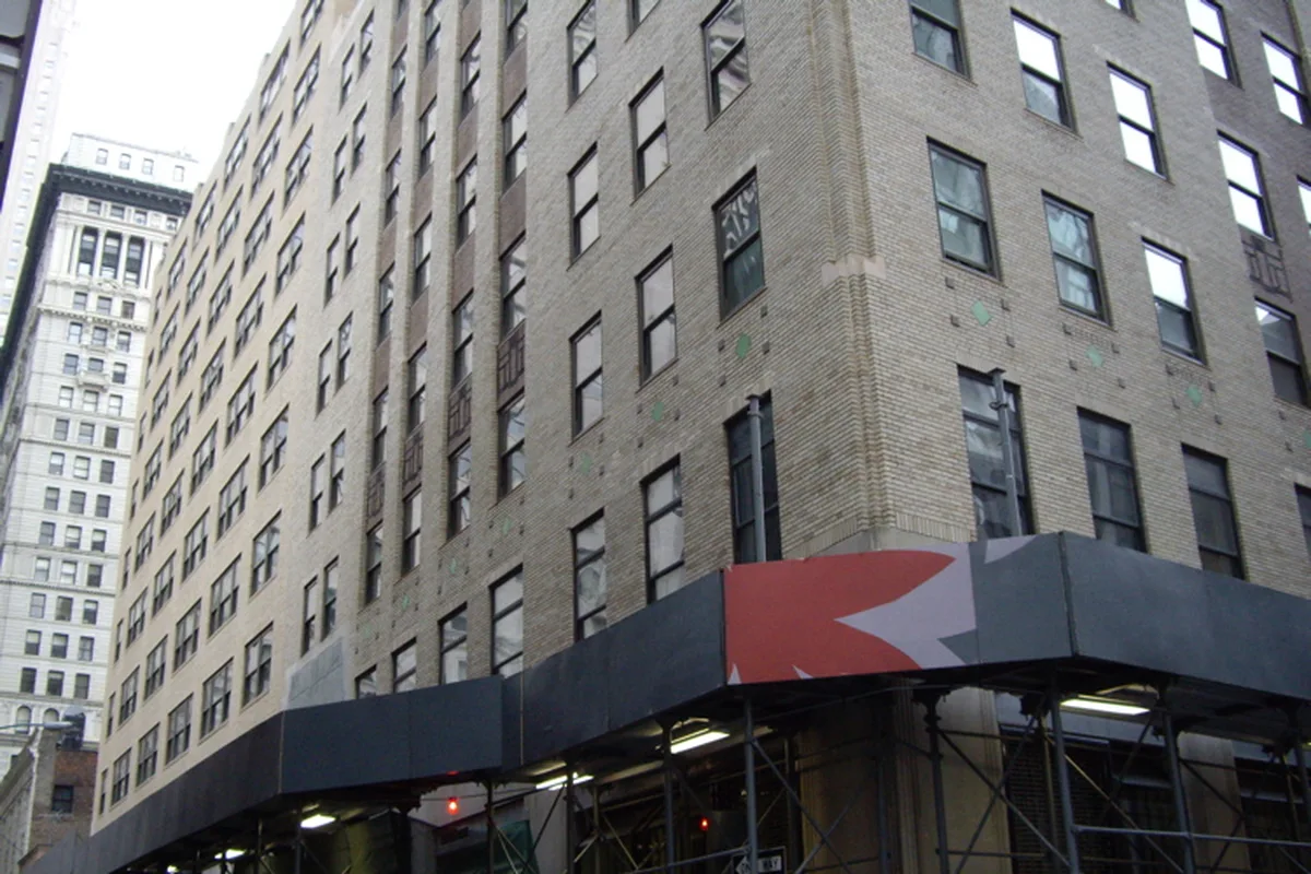 The lower floors of 88 Greenwich Street at Rector Street, beige brick with green terra-cotta accents above a sidewalk shed