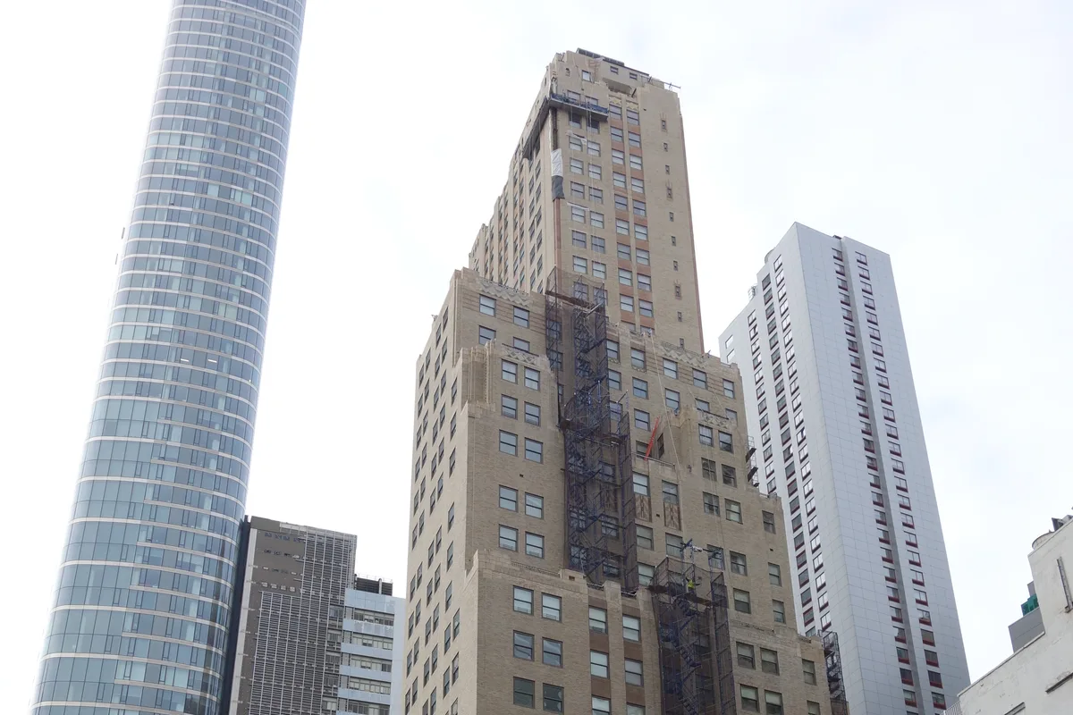 The stepped beige brick Art Deco tower of 88 Greenwich Street rising between newer Financial District towers